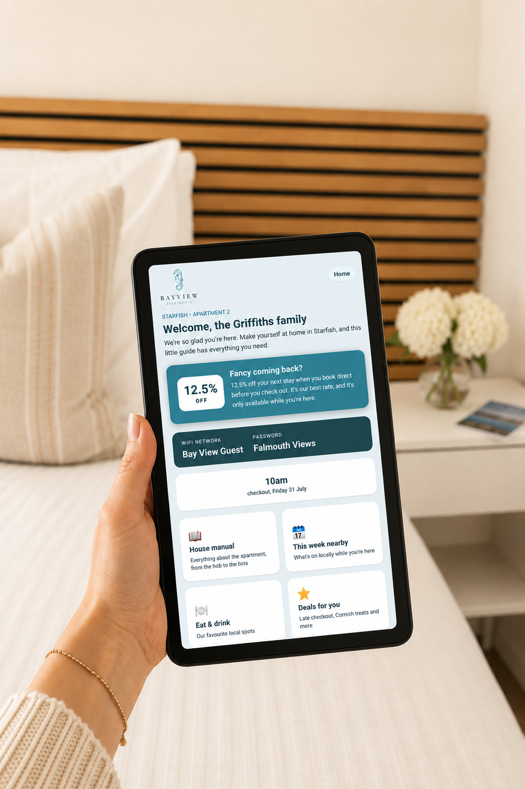 A guest holding an in-room tablet showing the Guest and Go concierge welcome screen